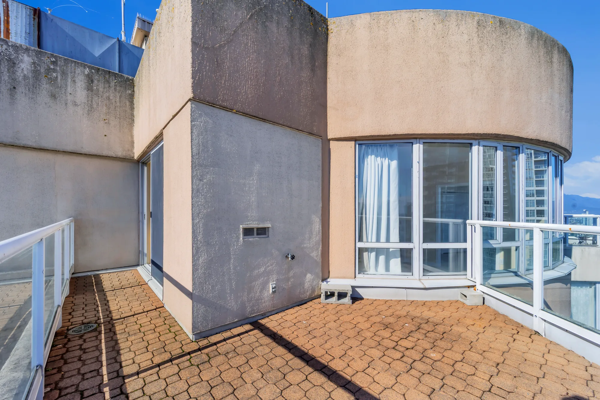 The balcony beside the curved bay of windows, the stucco walls of the top floor