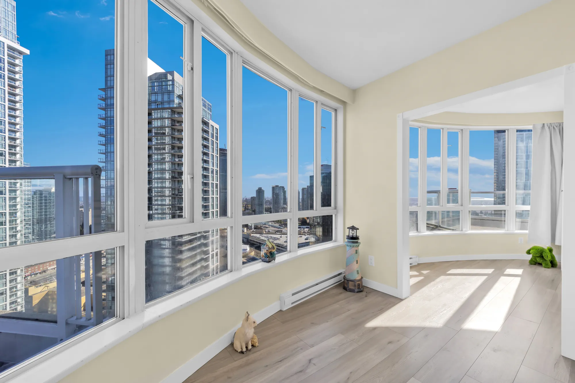 Along the curved wall of windows toward a wide opening into the next room, the towers outside, a balcony railing at the left