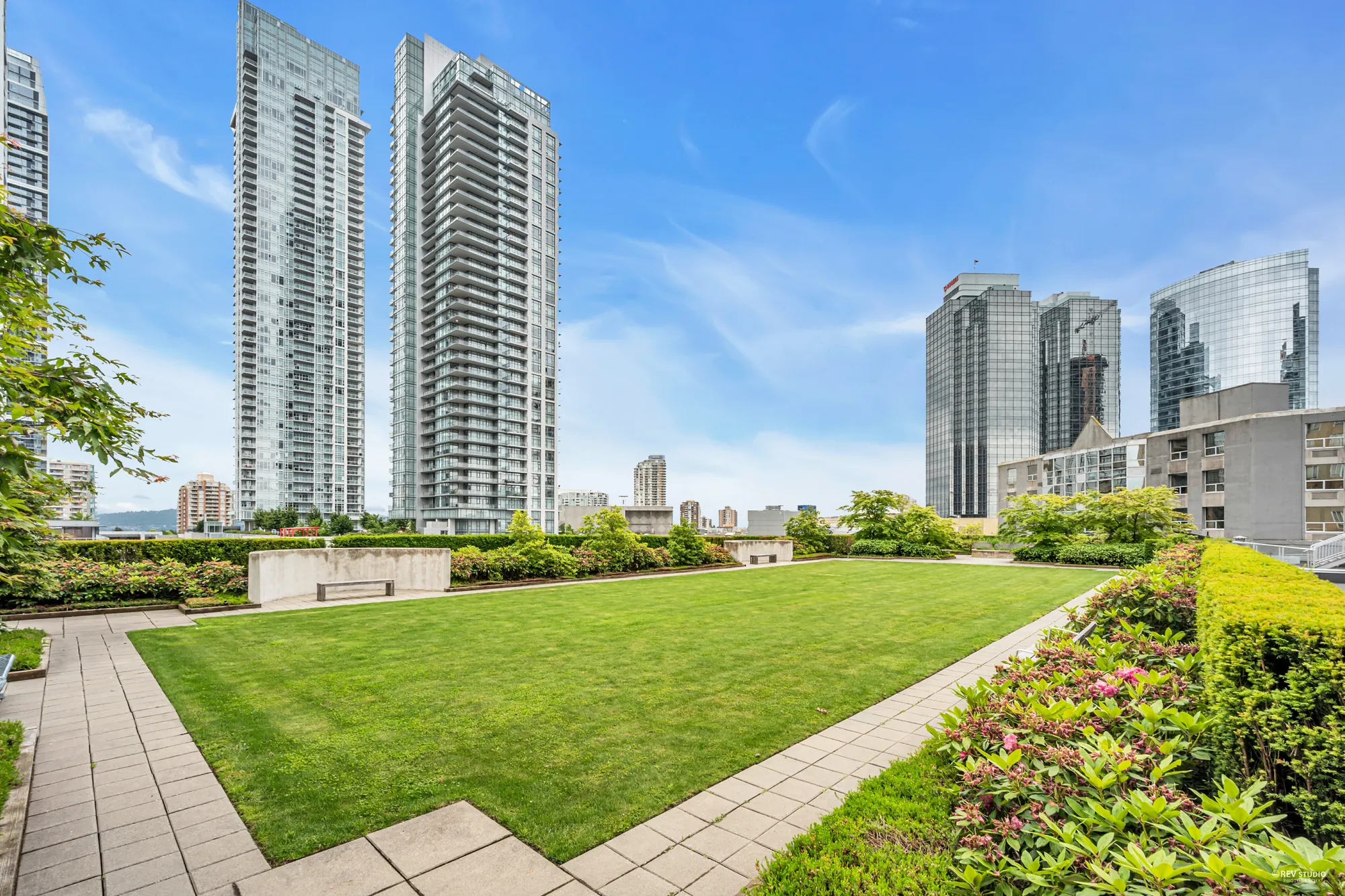 A lawn edged by flower beds and paths, towers around it